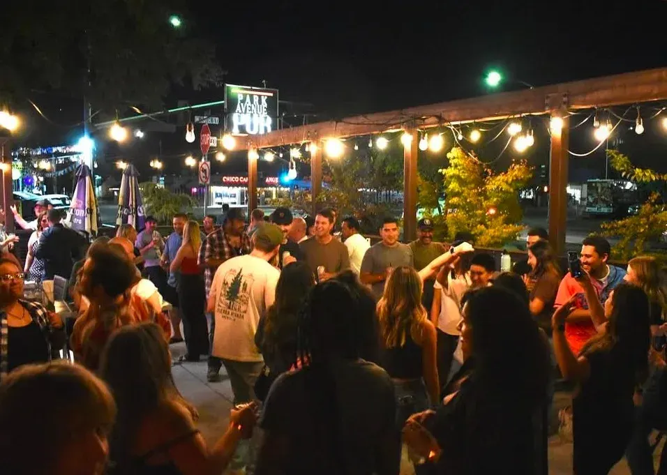 Singles laughing on a string-lit pub patio at night